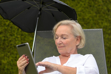 Rentnerin mit einem Tablet in ihrem Garten
