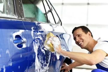 professionelle Fahrzeugwäsche, lächelnder Mann reinigt Auto