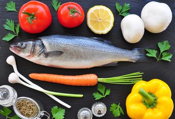 raw fish with fresh vegetables on a black background