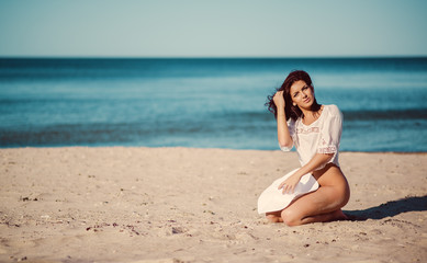 Fototapeta na wymiar Beautiful young brunette posing on the beach near the sea