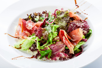 Restaurant food closeup - salad with prosciutto and vegetables