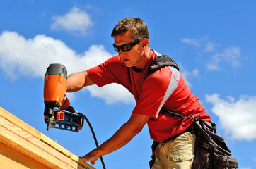 Building contractor worker with a air nail gun   - obrazy, fototapety, plakaty