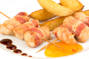 Thin rolls of bacon with slices of fried potatoes