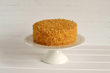honey cake on a stand on a light wooden background