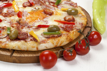 Pizza with several kinds of meat products, mushrooms and cheese on a table.