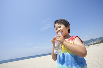 青空とビーチと水を飲む子供