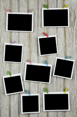 empty black photo frames hanging with clothespins on wooden back