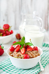 Oatmeal porridge with berries in a white bowl