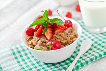 Oatmeal porridge with berries in a white bowl