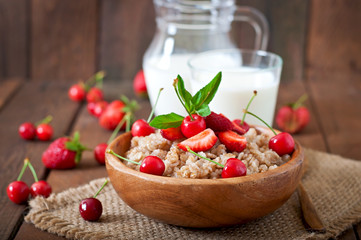 Oatmeal porridge with berries in a wooden bowl