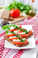 Fototapeta na wymiar Useful dietary sandwiches with mozzarella, tomatoes and rye bread