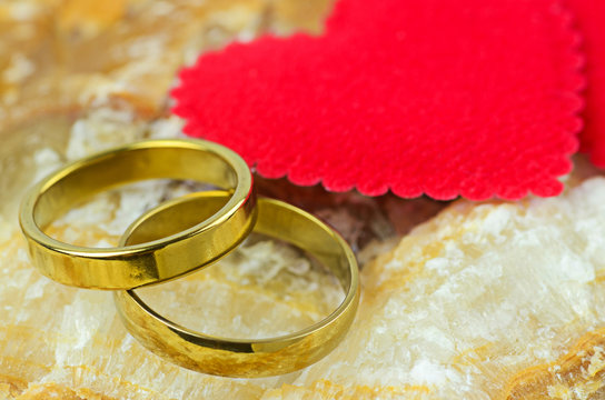 couple of gold rings on marble stone background