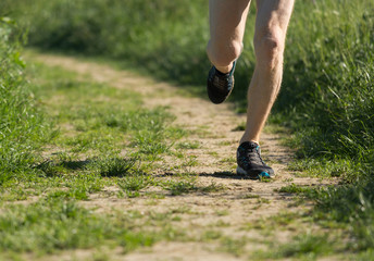 Fototapeta na wymiar Close up of legs of a man running on a path in the countryside.
