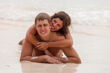 Fototapeta premium Young couple lie on the ocean beach