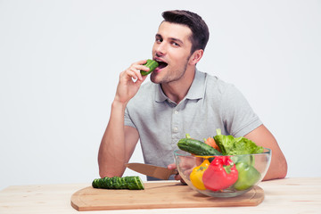 Man preparing salad and biting cucumber