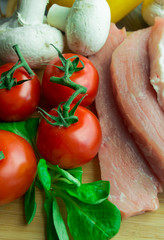 Raw pork on cutting board with  tomatoes and mushrooms