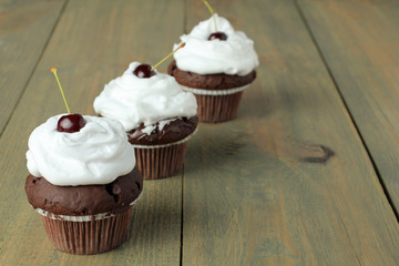 Chocolate Cupcakes with cherries on wooden background