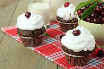 Chocolate cupcakes with cherries on wooden background. top view