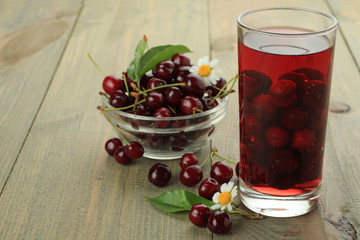 Closeup of fresh juice with sweet cherries on a wooden background
