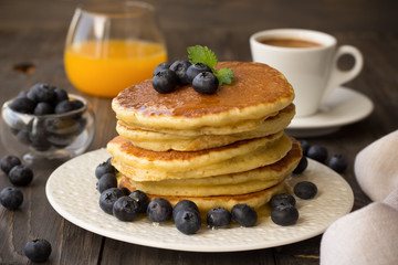 Pancakes with fresh blueberries and honey on wooden table 
