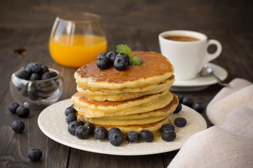 Pancakes with fresh blueberries and honey on wooden table 