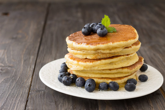 Pancakes with fresh blueberries and honey on wooden table 