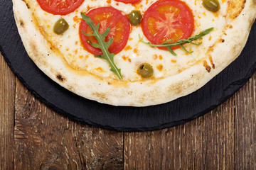Pizza vegetarian on plate on stone black try with fresh tomatoes