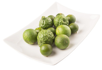 Lime, makrut or kaffir lime and calamansi on white plate