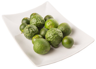 Lime, makrut or kaffir lime and calamansi on white plate
