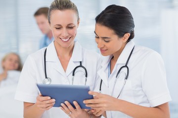 Doctors looking at clipboard while his colleague is with patient