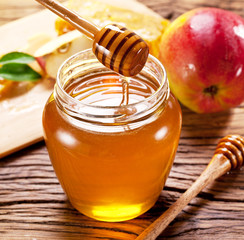 Glass can full of honey and wooden dripper.