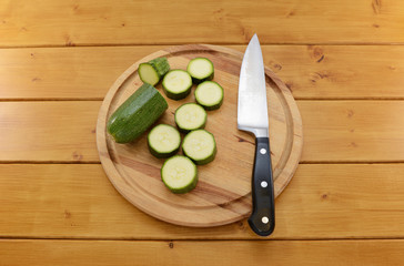 Courgette sliced with a knife on a chopping board