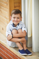 Portrait of a stylish boy on the street near the house