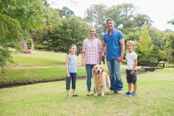 Happy family smiling at the camera with their dog