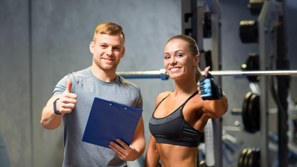 smiling young woman with personal trainer in gym