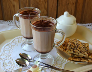 Two mugs with cocoa and cookies.