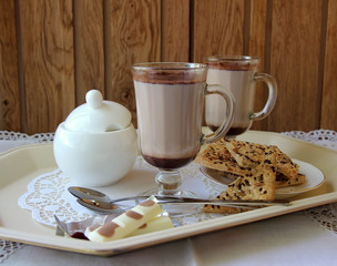 Two mugs with cocoa and cookies.