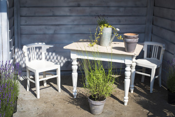 View of garden house with white retro wooden furniture decorated with flower pots