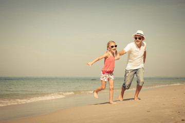 Father and daughter playing on the beach at the day time.