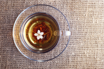 cup of black tea with apricot flower on canvas , top view