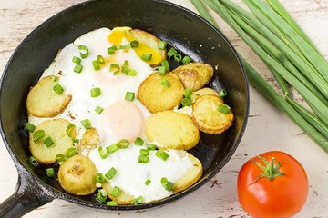fried potatoes with fried eggs in a frying pan