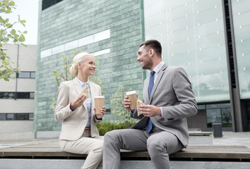 smiling businessmen with paper cups outdoors