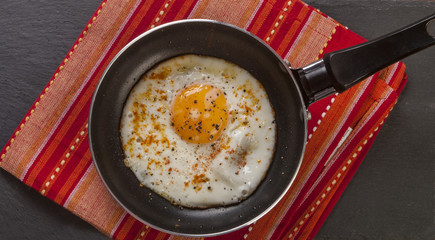Fried egg on frying pan top view close up