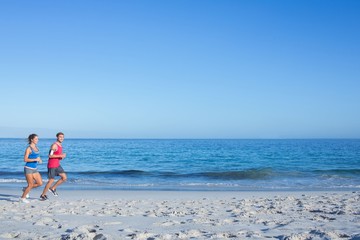 Happy couple running together beside the water