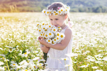 Cute little girl with bouquet of chamomiles