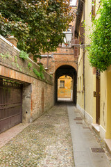 Fototapeta premium Small ancient street in the old downtown of Ferrara, Italy