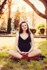 pregnant woman stands next to the sunset in the garden