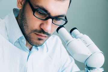 Young male doctor viewing through microscope