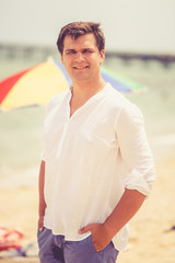 Toned portrait of smiling handsome man posing on sunny beach