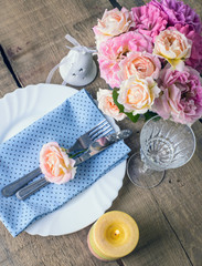 Beautiful festive table setting with roses, candles and napkins 